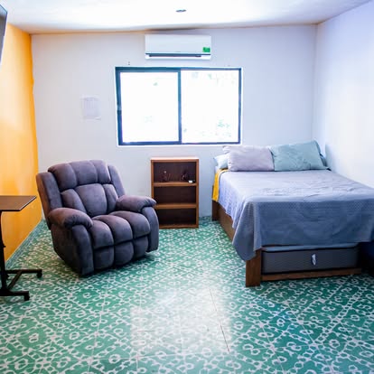 Habitación amplia del centro con butaca reclinable y cama